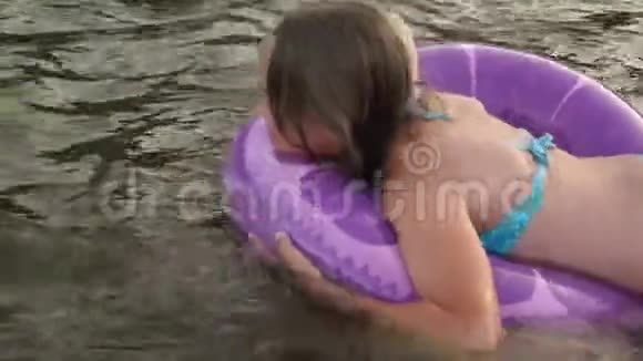 穿着泳衣的女孩在救生圈的水面上漂浮着笑了起来海滩季节视频的预览图