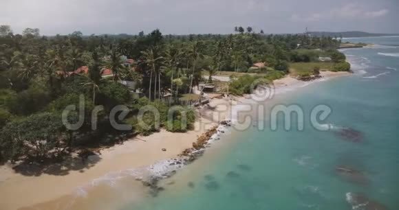 无人机飞来飞去的小田园海洋度假村房子里有棕榈树海浪用清澈的碧水冲刷着海岸视频的预览图