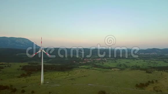 风力发电机在森林和山电发电厂大片草地景观上的空中镜头视频的预览图