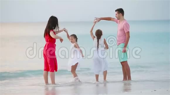 父母和可爱的两个孩子在海滩上的暑假里玩得很开心四口之家相爱幸福视频的预览图