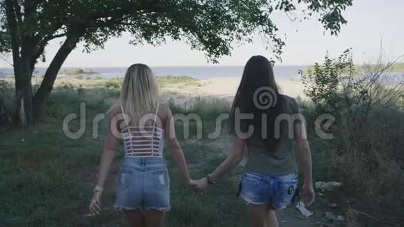 两个朋友的女人在路上跑步旅行金发女郎和黑发女郎微笑着在假期里玩得很开心Stadicam视频的预览图