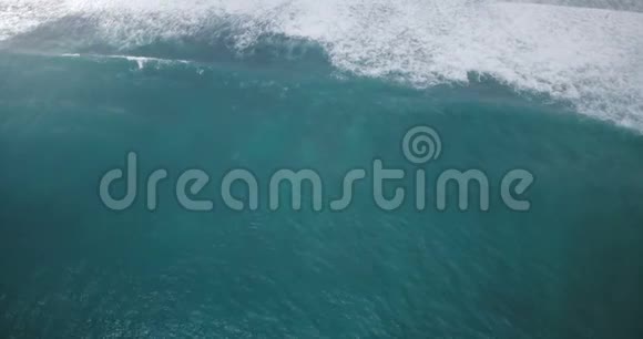 无人机在海水表面下降和放大巨大的薄荷蓝色汹涌的海浪随着泡沫而坠落视频的预览图