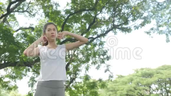 运动的年轻亚洲女人在公园日出前热身和伸展运动视频的预览图
