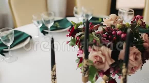 节日婚礼餐桌设置绿色鲜花餐巾纸眼镜和烛台桌子装饰特写视频的预览图