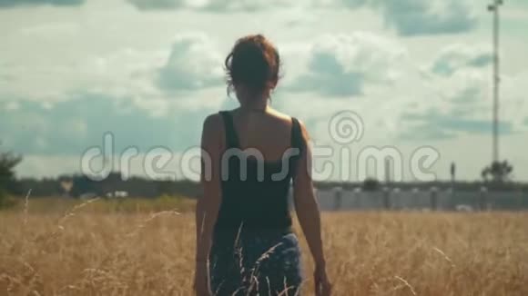 悲伤的女孩在灿烂的阳光下沿着金色的田野散步视频的预览图