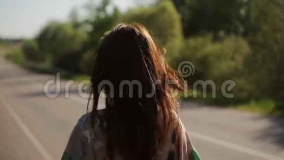 一位身穿连衣裙的美丽黑发女子沿着乡间的道路散步她看着一片风景如画的草坪草地上绿树成荫视频的预览图