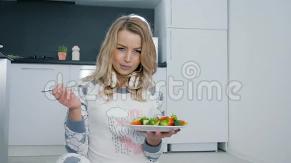 健康的生活方式年轻女人穿着睡衣坐在地板上吃切菜视频的预览图