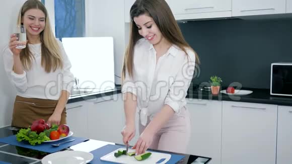 在厨房背景下一个女朋友用一杯水在切菜板上切黄瓜做沙拉视频的预览图
