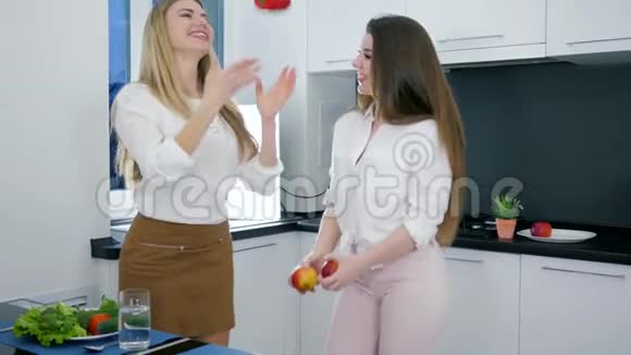 在厨房里玩得开心手里拿着产品的女孩在烹饪中跳舞和大笑视频的预览图
