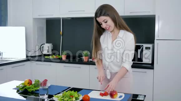 健康的饮食女孩在厨房桌上的砧板上切红椒做沙拉视频的预览图