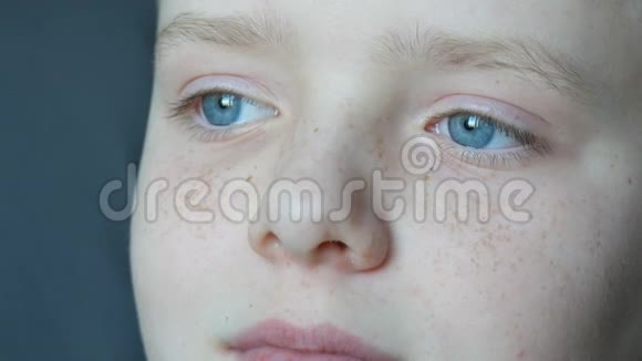 脸的美丽少年用雀斑特写一个蓝眼睛的男孩望着远方视频的预览图