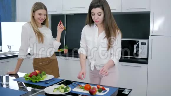 饮食和适当的营养女孩们在家里的厨房品尝和准备新鲜蔬菜沙拉视频的预览图