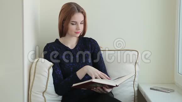 美女坐在家窗台看书视频的预览图
