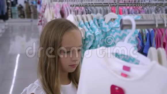年轻的金发女孩选择时尚服装精品店视频的预览图