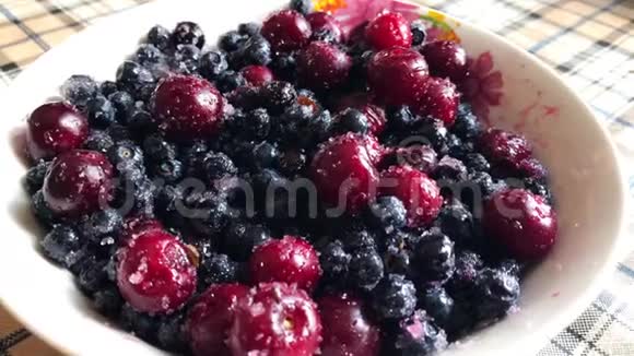 蓝莓和樱桃在糖和白色盘子里视频的预览图