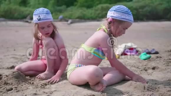 两个女孩在海滩上玩耍做沙子夏日炎炎海上家庭假日视频的预览图