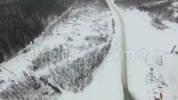 在恶劣的冬季阴天大雪纷飞在农村公路上穿过森林视频的预览图