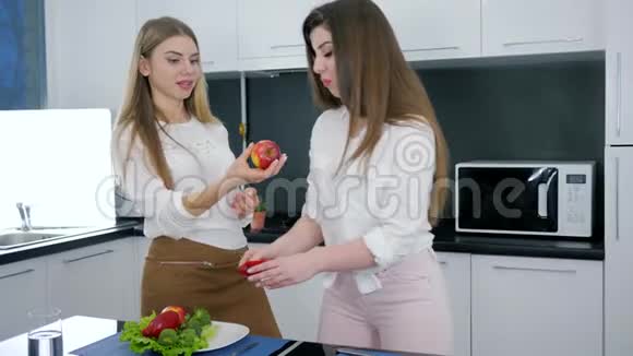 女朋友在厨房里聊天在餐桌上准备沙拉女孩子在切割板上切苹果视频的预览图