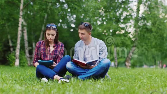 学生们坐在草地上一个男人在看书一个女人在用平板电脑视频的预览图
