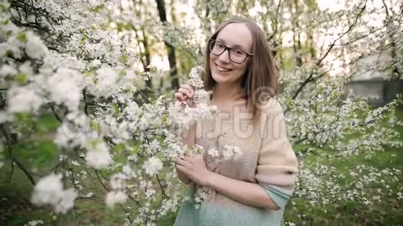 美丽的女孩正在一个盛开的春天公园里微笑着为相机摆姿势视频的预览图