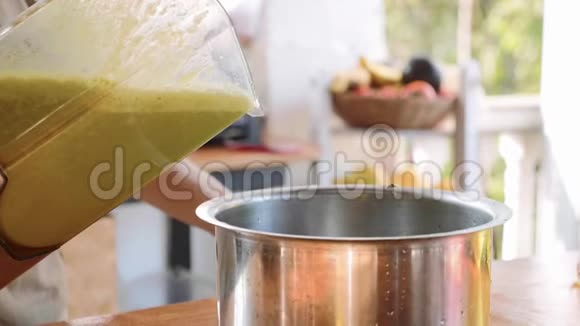 厨师用搅拌器在平底锅中倒入绿色菠菜奶油汤视频的预览图