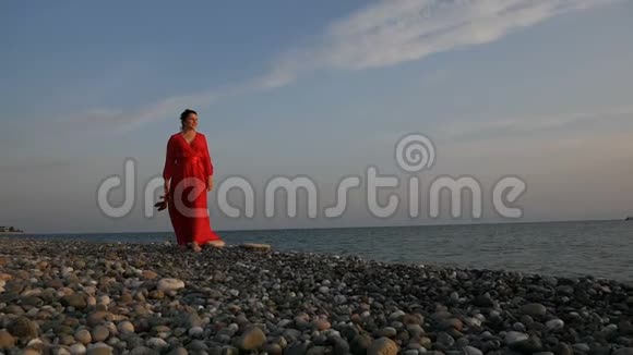 夏天日落时分在沙滩上散步的女人视频的预览图