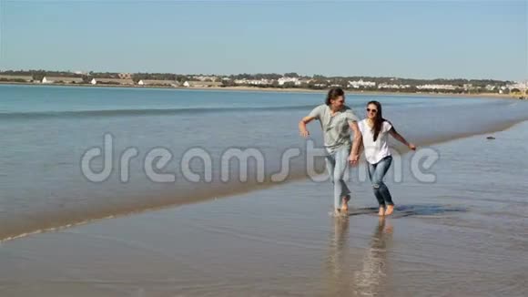 海滩暑假夫妇在假期跑步快乐的海滩度假情侣一起笑着玩视频的预览图