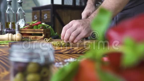用刀子在厨房桌子上手工切割绿色橄榄烹饪切片橄榄素沙拉可供选择的成分视频的预览图
