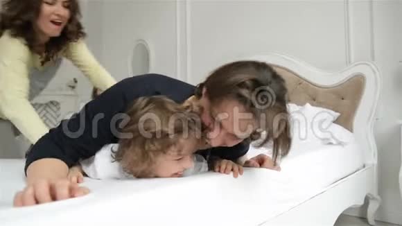 英俊的丈夫和漂亮的妻子和两个孩子躺在白色的床上有趣的父母有迷人的微笑视频的预览图