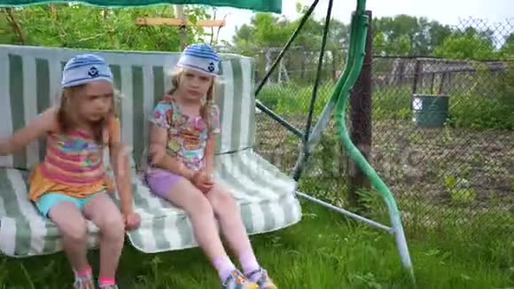 两个女孩姐妹在荡秋千娱乐和户外娱乐活动夏日视频的预览图