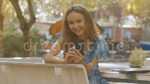 公园桌旁智能手机上的金发女郎照片视频的预览图