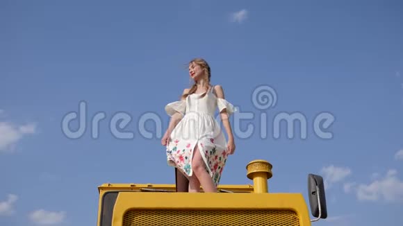有魅力的年轻女子在黄色拖拉机上缓慢地旋转着视频的预览图