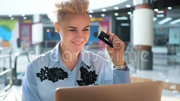 双手紧握信用卡室内使用笔记本电脑网上购物女人快乐视频的预览图