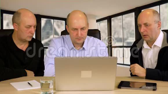 三个商人坐在桌前的手提电脑上商业项目视频的预览图
