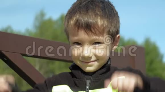 一个学龄前男孩坐在公园的长凳上把保护放在他的头膝盖和手臂上夏季视频的预览图