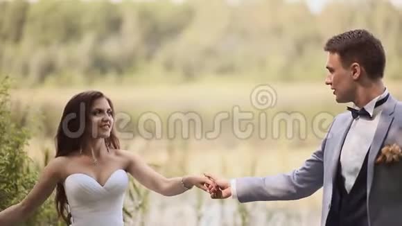 新娘和新郎在湖边的公园里户外跳舞一起快乐结婚纪念日视频的预览图