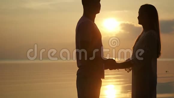 恋爱中的年轻夫妇在令人惊叹的日落中互相看着牵手慢动作1920x1080视频的预览图