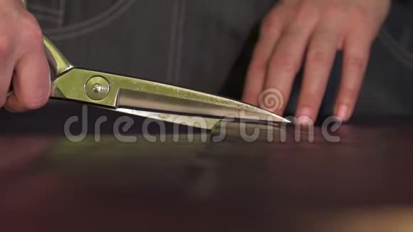 女人手剪剪刀剪桌子上的皮做皮具视频的预览图