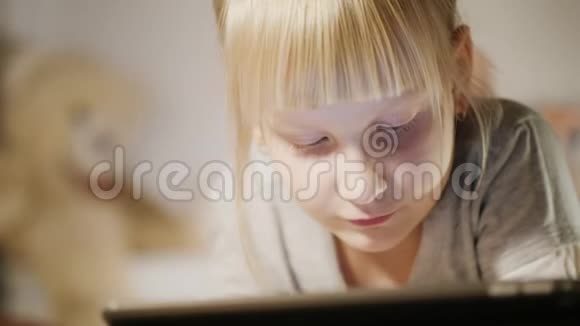 靠近一个女孩躺在床上用数字平板电脑儿童和技术概念视频的预览图