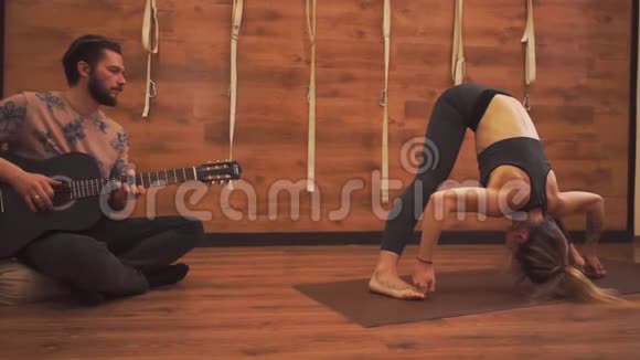 年轻女孩练瑜伽男人弹吉他视频的预览图