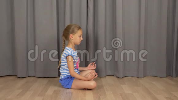 年轻女孩坐在禅坐在客厅的地板上打坐女孩练习瑜伽视频的预览图