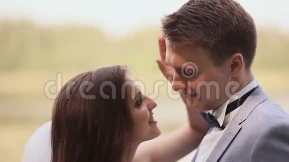 年轻夫妇新郎和新娘一起在大自然中他们互相看着傻瓜接吻一起快乐结婚纪念日视频的预览图