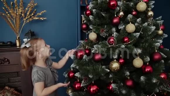 非常漂亮的小女孩站在新年树附近触摸玩具视频的预览图
