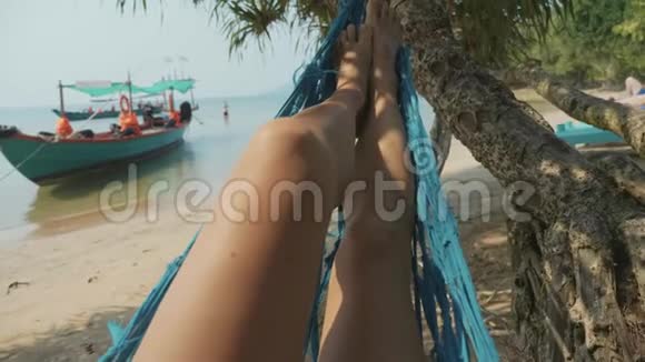 年轻女子的脚慢慢地躺在沙滩吊床上视频的预览图