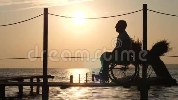 残疾人男女对抗太阳的剪影海滨的浪漫相遇视频的预览图