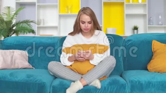 女人坐在沙发上一边看电话一边等待短信或电话视频的预览图