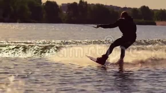 在金色夕阳下滑雪板骑手在飞溅的水中快速前进视频的预览图