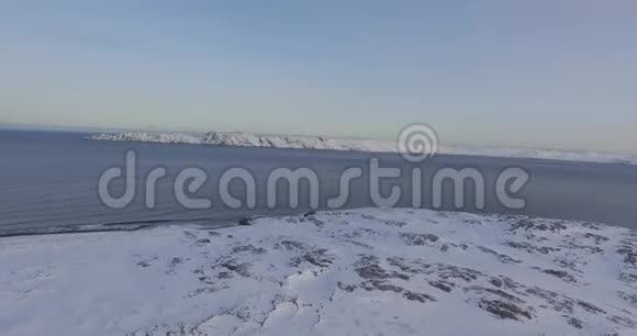 灰蒙蒙的天空下未冻的海湾被雪覆盖的地面视频的预览图