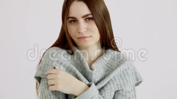 穿着一件暖和的毛衣的美丽的欧洲女孩站在白色的墙上情绪平静和微笑视频的预览图