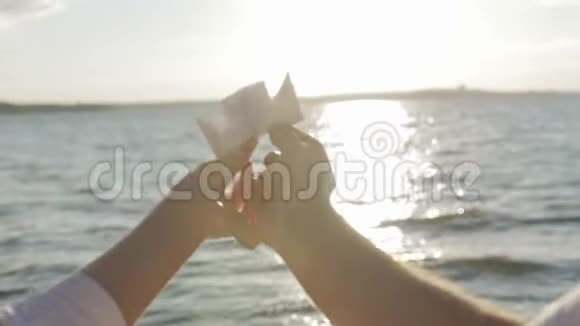 纸船在恋人手中飘浮在阳光普照的小路上视频的预览图
